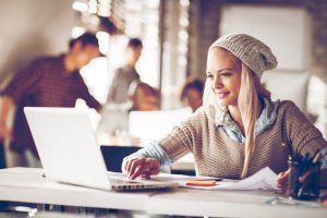 Picture of freelance designers working together in an office,focus is on blond young woman using laptop